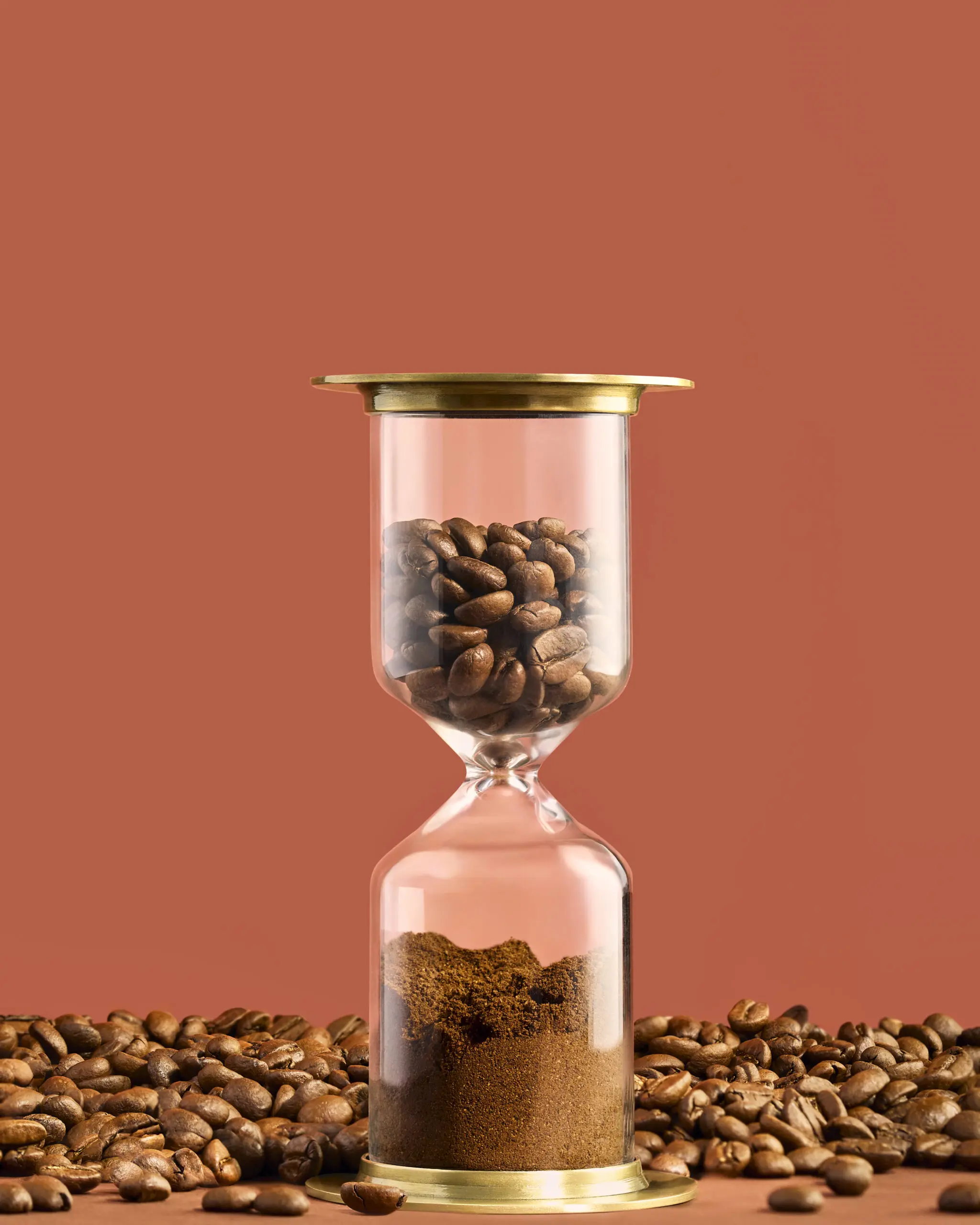 Clessidra con chicchi interi e caffè macinato Penazzi 1926 su sfondo marrone, a rappresentare il tempo e la cura nella tostatura artigianale