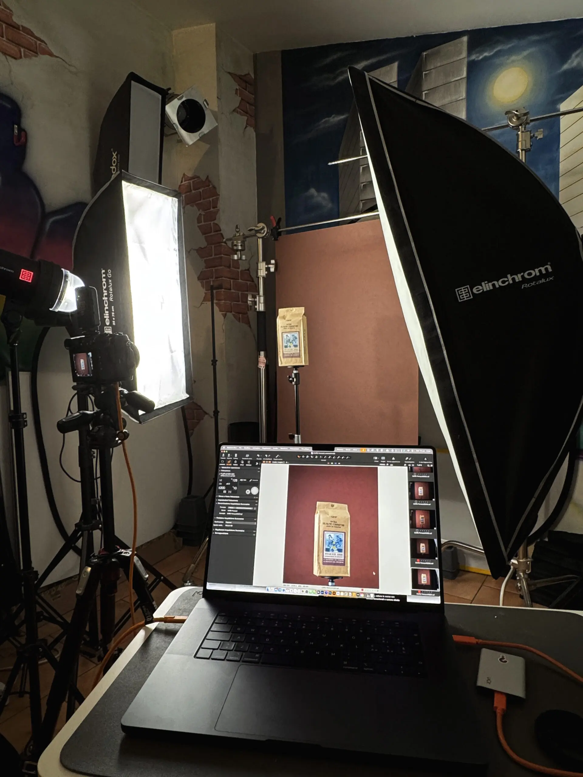 Postazione fotografica professionale con fotocamera, luci softbox Elinchrom e laptop che mostra uno scatto di un pacchetto di caffè in Capture One.