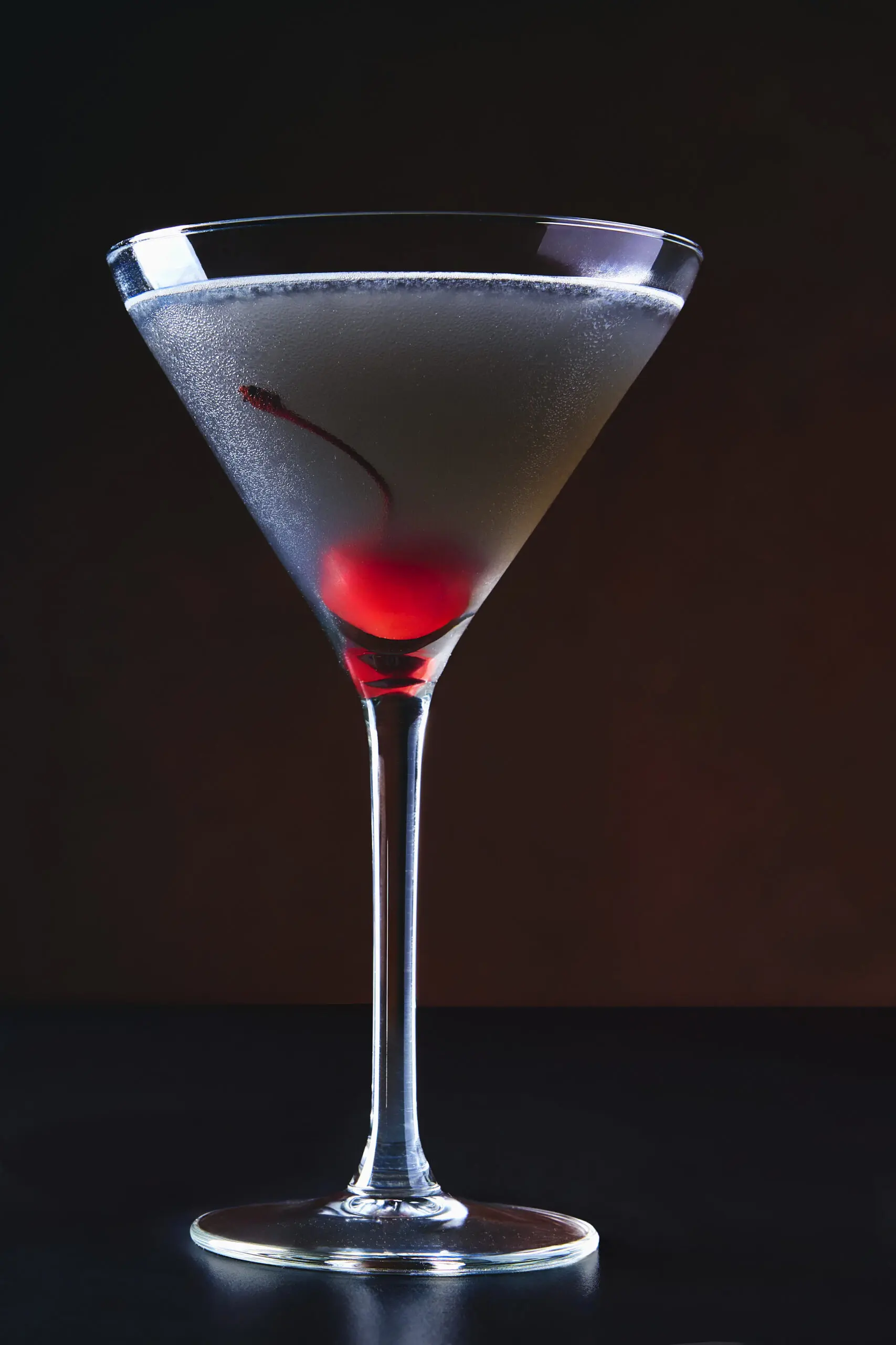 Cocktail in coppa martini con dettaglio rosso sul fondo e luce da studio
