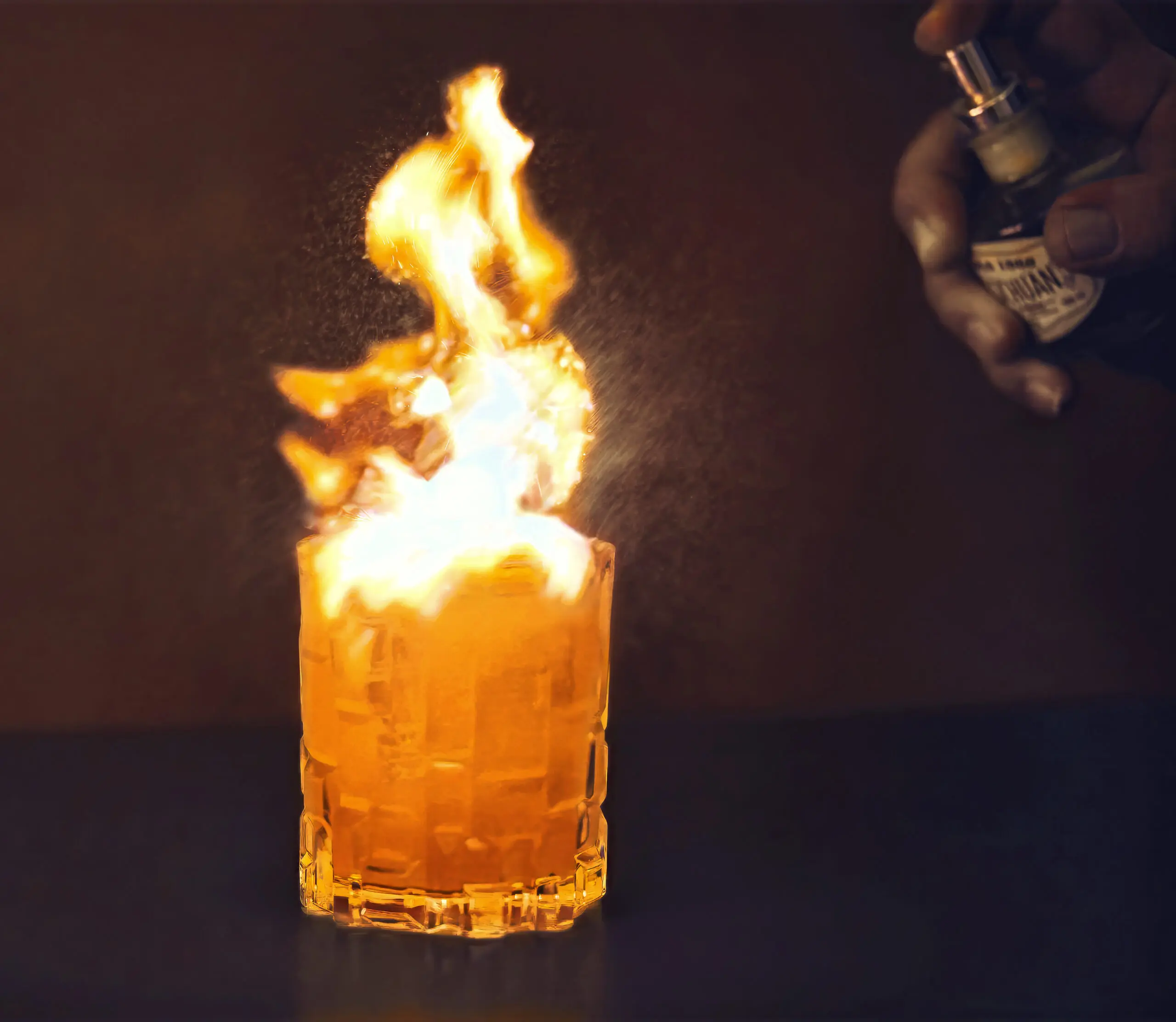 Cocktail in bicchiere basso con fiamma alta su sfondo scuro, stile cocktail bar