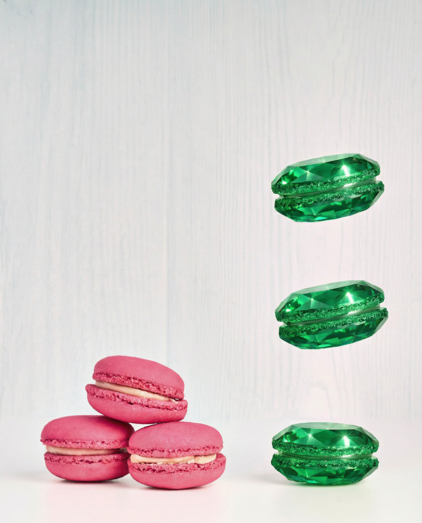 Tre macaron rosa appoggiati e macaron verdi effetto gemma sospesi su sfondo chiaro.